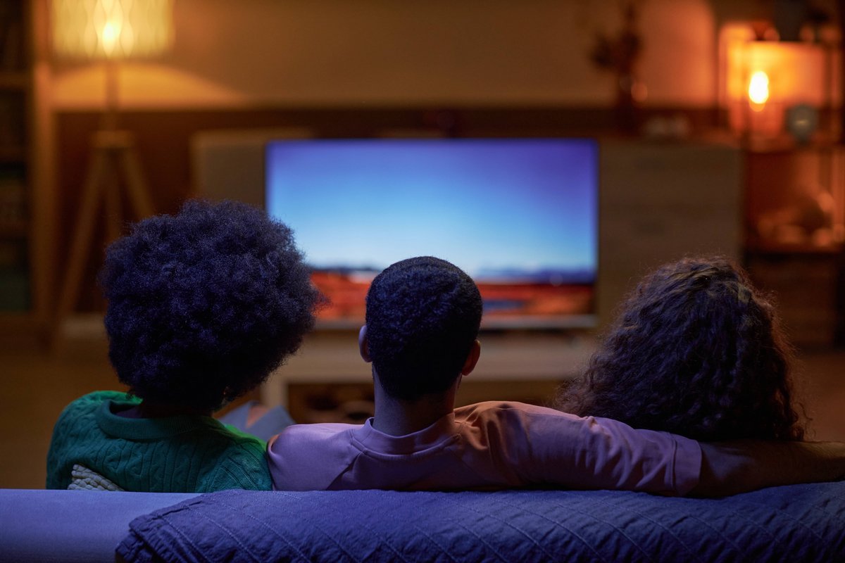 trois personnes regardant la TV