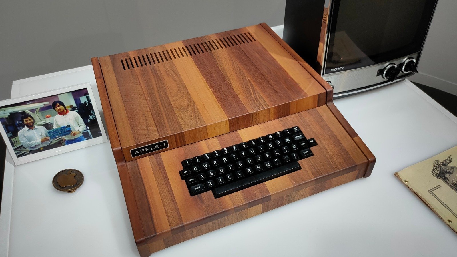 Une réplique de l'Apple I et son boîtier en bois tropical (Koa). À gauche, une photo de Steve Wozniak et Steve Jobs datant à peu près de la même époque. ©Shutterstock