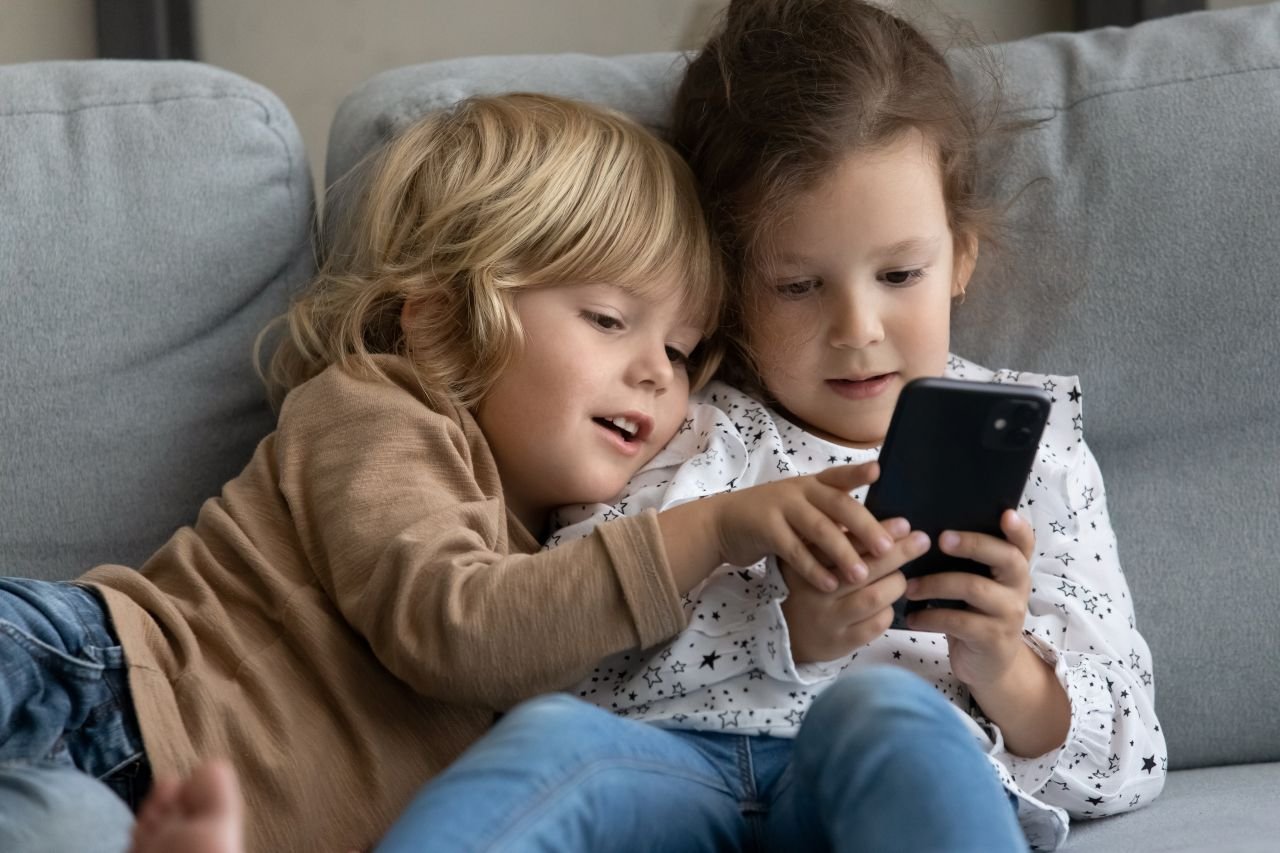 Des enfants utilisant un smartphone. ©fizkes / Shutterstock