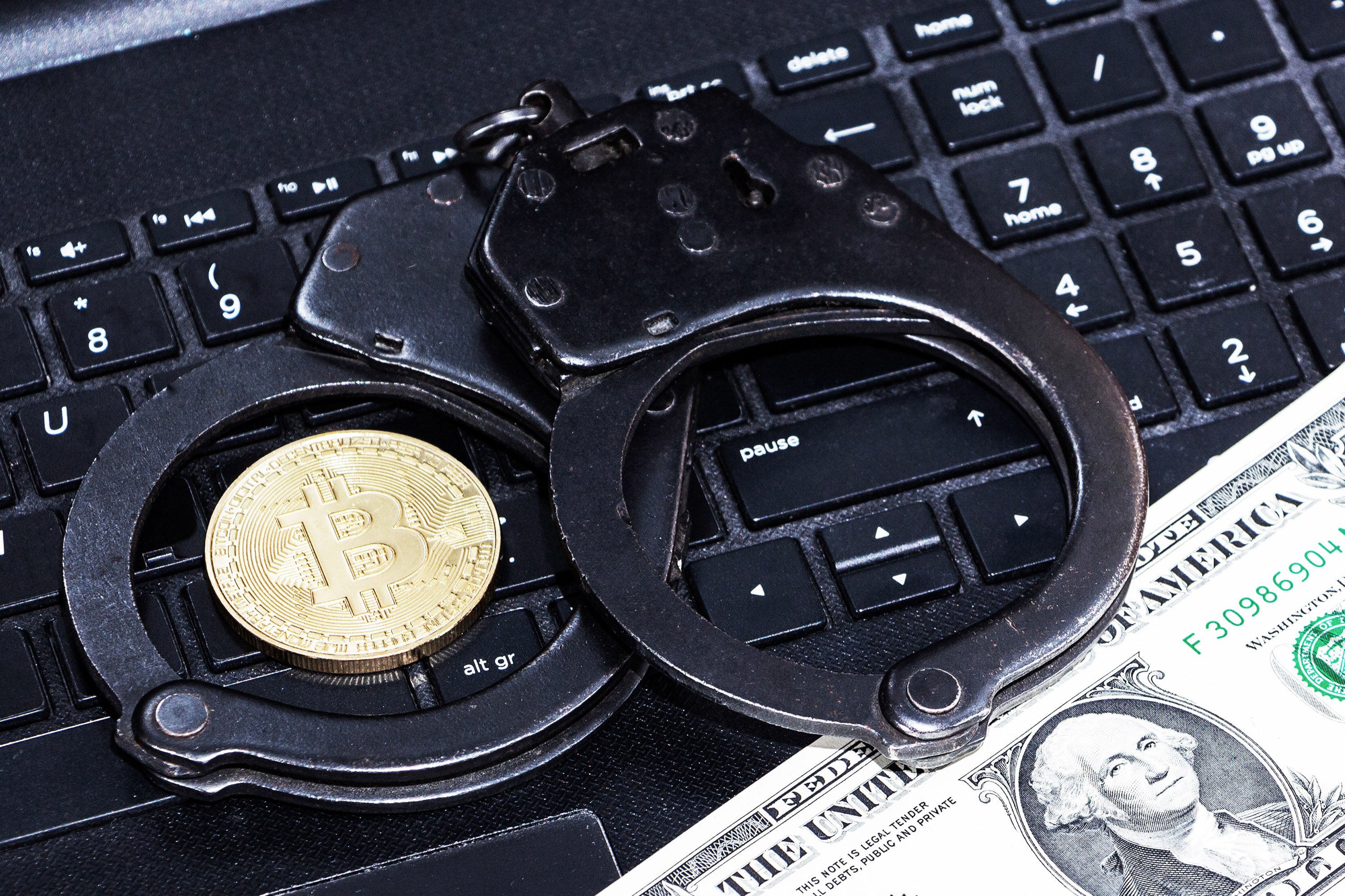 Une pièce estampillée Bitcoin posée à côté de menottes © Shutterstock.com