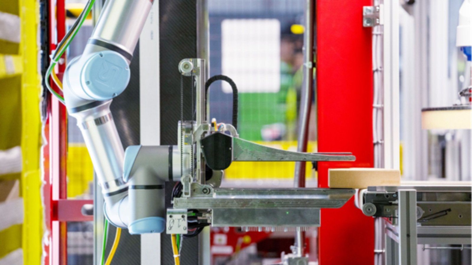 Un bras robotisé saisit un colis sur une ligne logistique. © Amazon