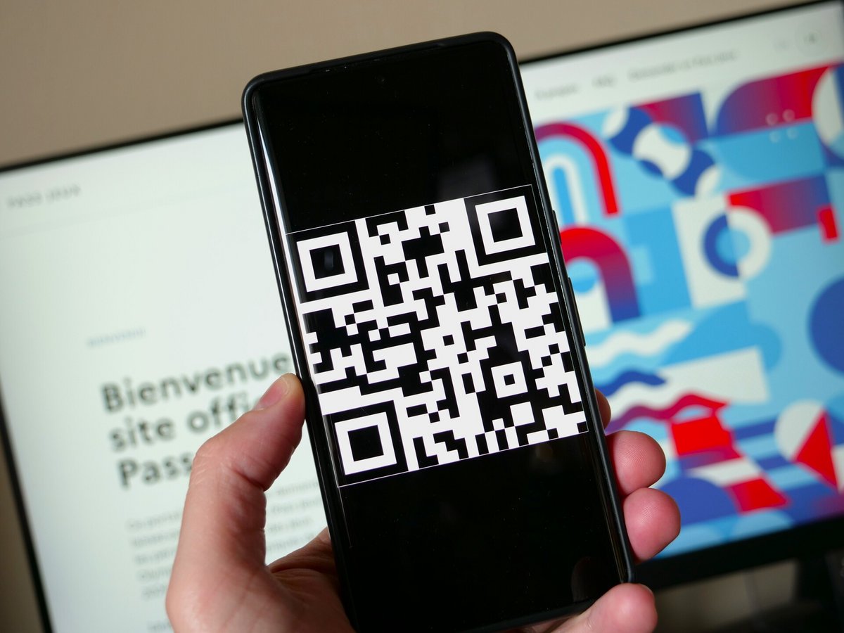 Un QR Code affiché sur un smartphone devant la page d'accueill du site officiel de Pass Jeux © Alexandre Boero / Clubic