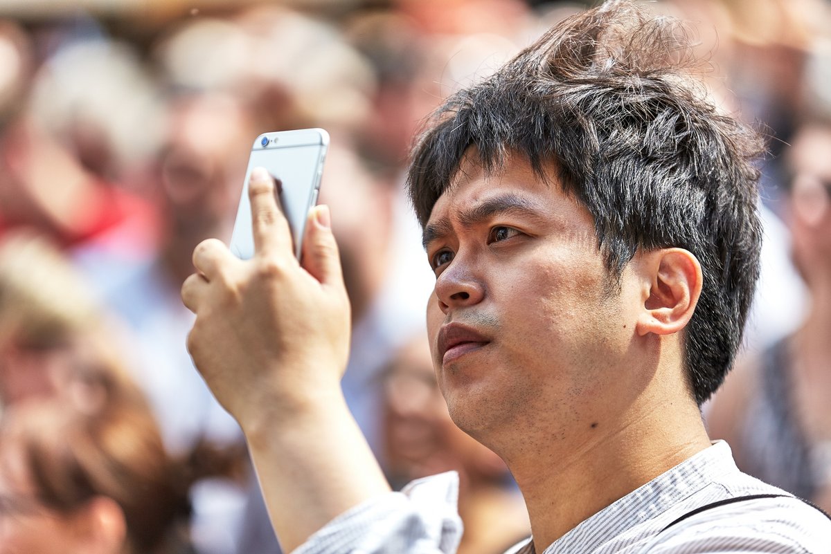 Un homme prenant un paysage en photo avec son smartphone © Miroslav Denes / Shutterstock.com