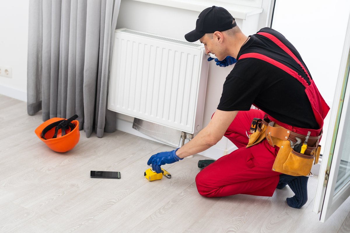 Un homme en train d'installer un radiateur © Andrew Angelov / Shutterstock