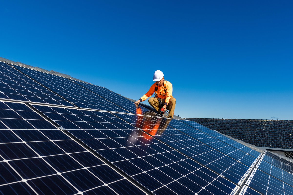 Un technicien en train de poser des panneaux photovoltaïques © zstock / Shutterstock