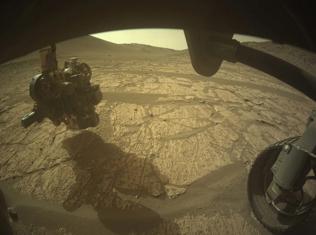Le bras robotisé étudie le sol, avec en fond la vallée de Neretva qui s'étend devant lui © NASA / JPL-Caltech