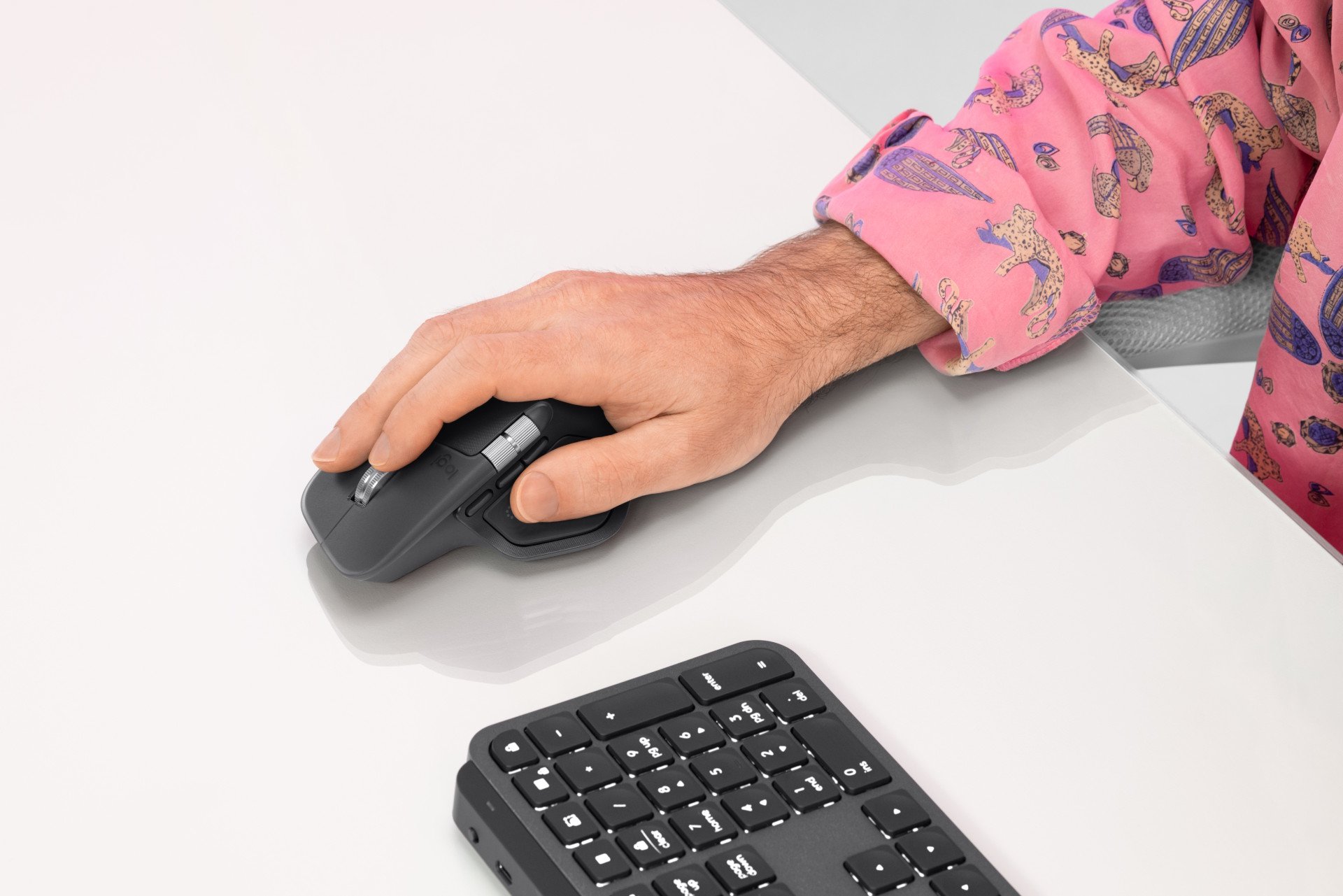 Sous le pouce de l'utilisateur, vous retrouverez le bouton à retour haptique de la MX Master 4. La chemise rose est optionnelle. ©Logitech