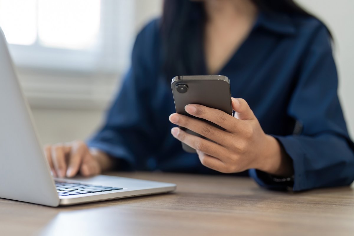 Femme qui tient un smartphone dans sa main © Natee Meepian / Shutterstock