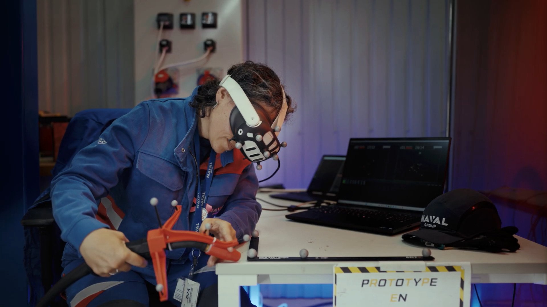 Chez Naval Group, une opératrice teste le prototype de Telewelder : casque de réalité virtuelle et capteurs de mouvement permettent de piloter à distance le bras robotisé de soudage, dans le cadre du projet européen JARVIS. © Naval Group