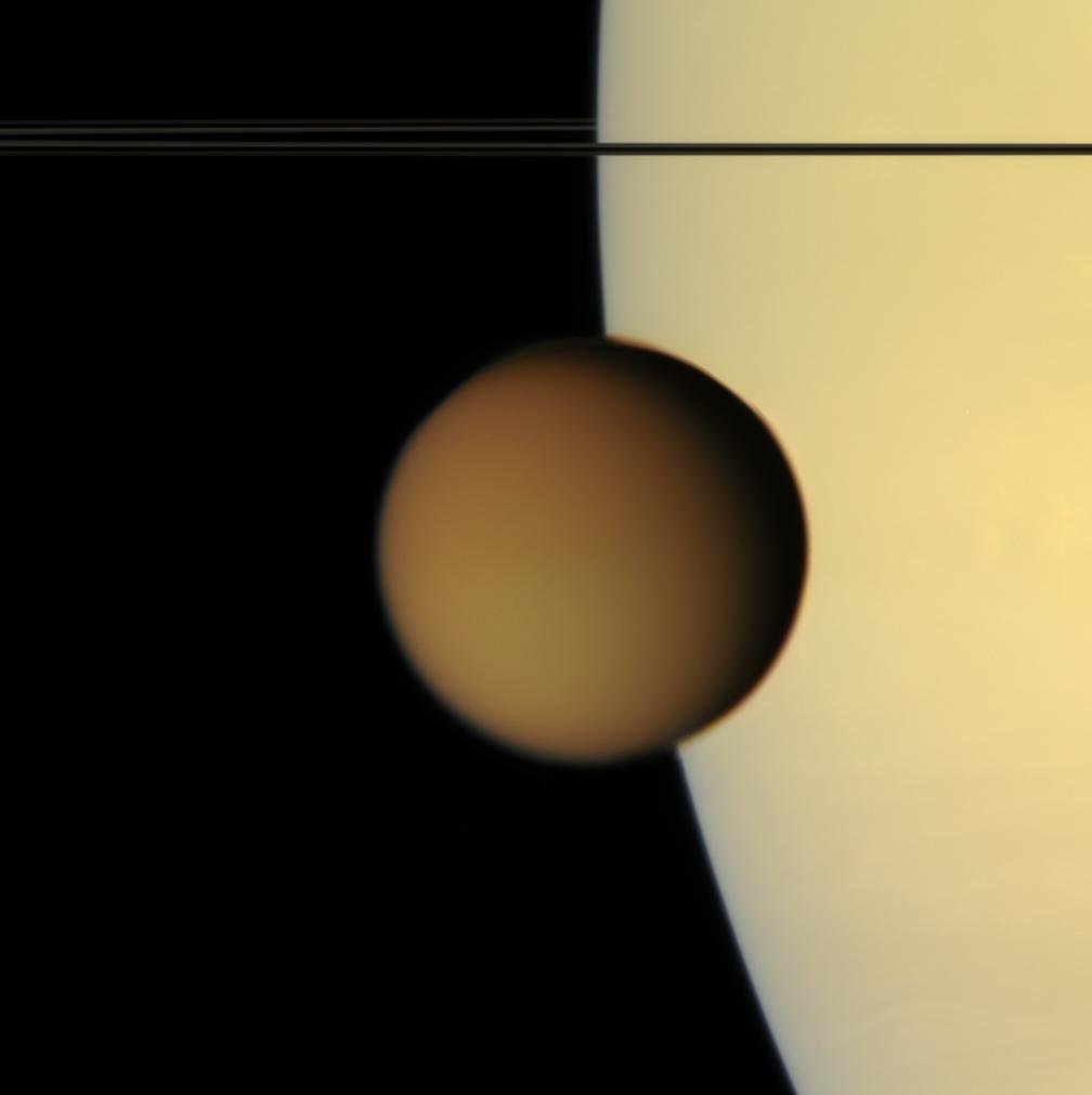 Titan et son épaisse atmosphère, observée avec Saturne en fond… Crédits : NASA/JPL-Caltech