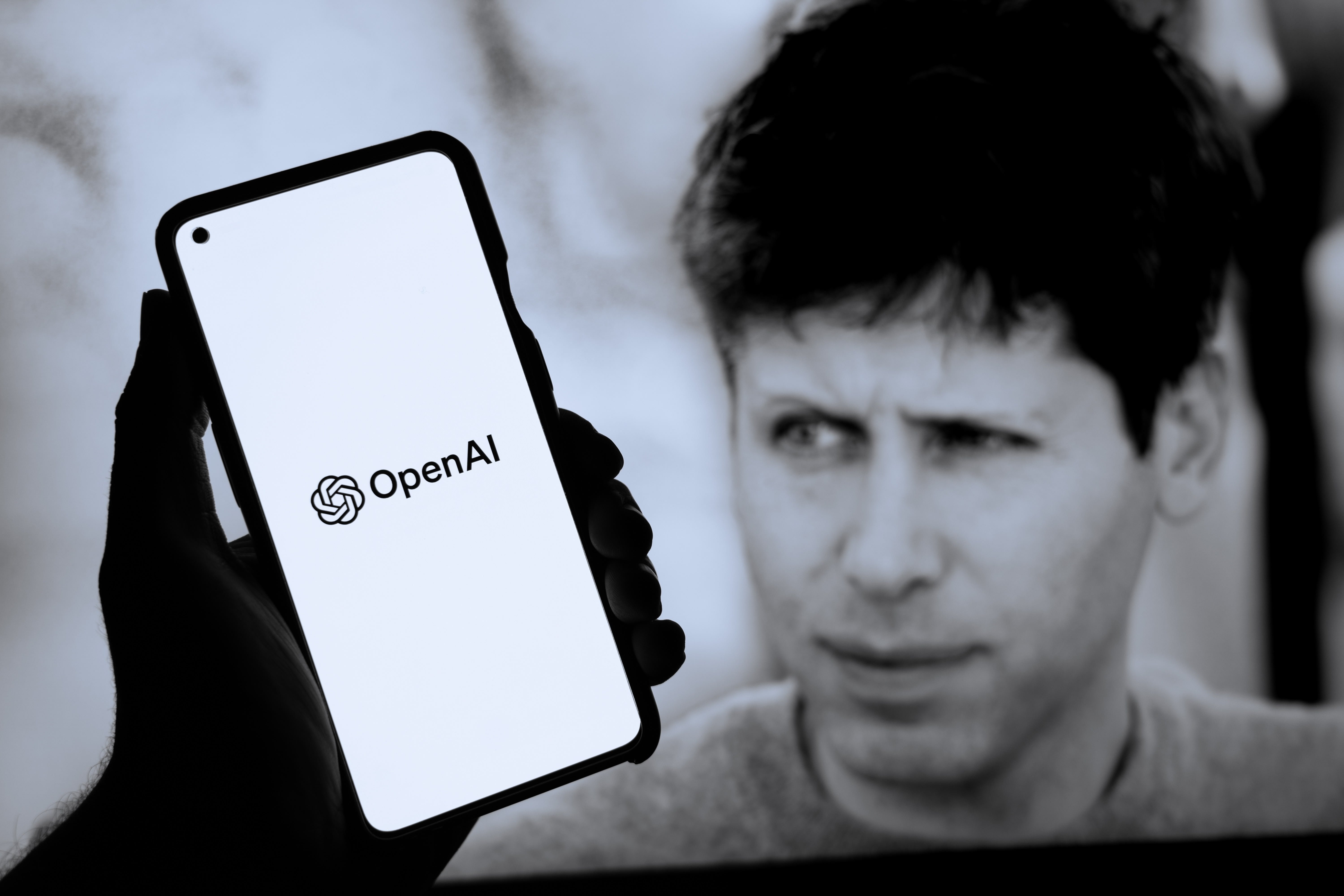 Une photo de Sam Altman mise à côté d'un smartphone affichant le logo d'OpenAI © Shutterstock