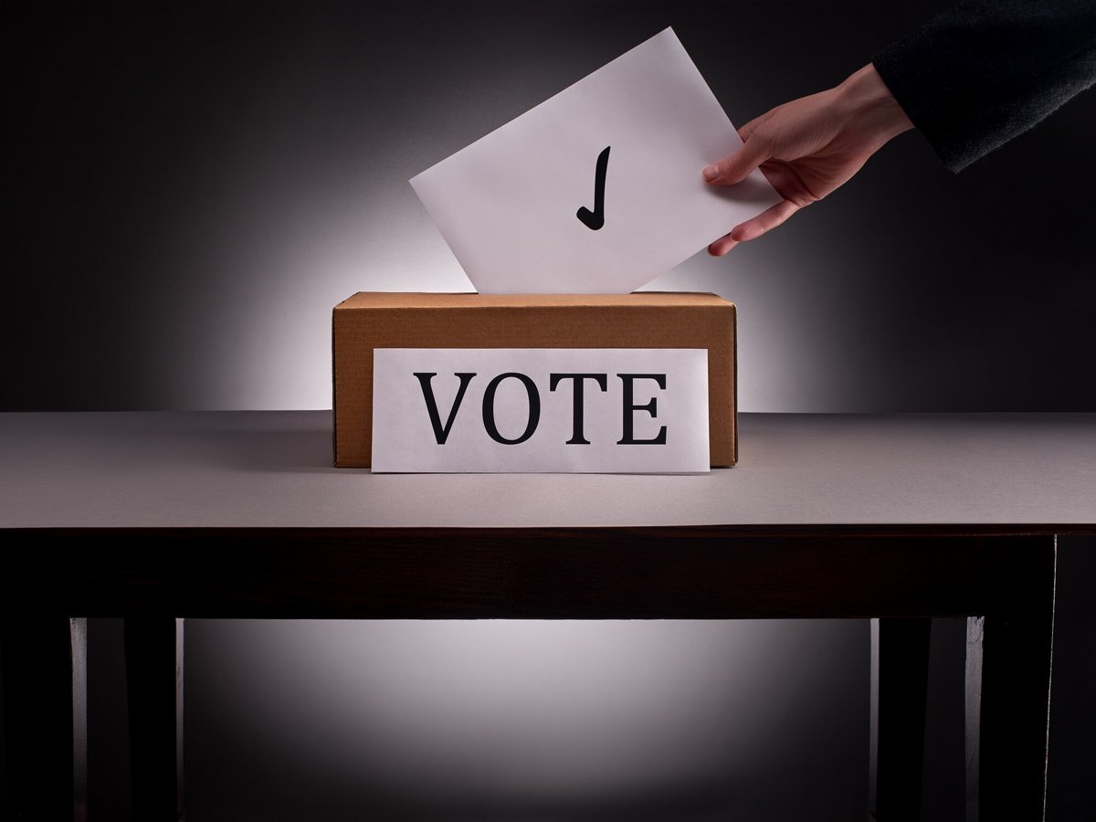 Une femme qui glisse un bulletin de vote, peut-être votera-t-on un jour pour des IA © Andrew Rafalsky / Shutterstock
