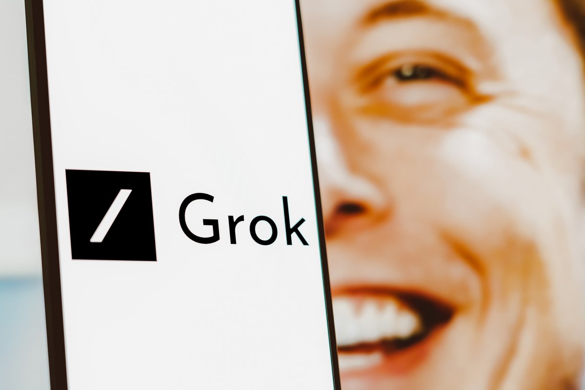 Le sigle de Grok affiché sur un smartphone, avec Elon Musk en fond © rafapress / Shutterstock