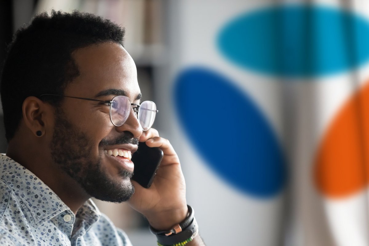 Un homme au téléphone avec, au fond, le logo de Bouygues Telecom © Shutterstock x Clubic.com