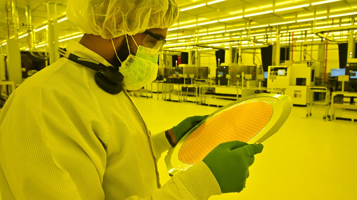 Sous la lumière ambrée (privée d'UV) un employé d'Intel examine un wafer à peine reçu © Intel