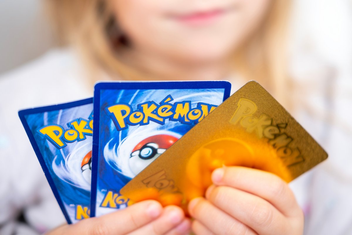 Un enfant qui tient des cartes Pokémon dans sa main © Kittyfly / Shutterstock