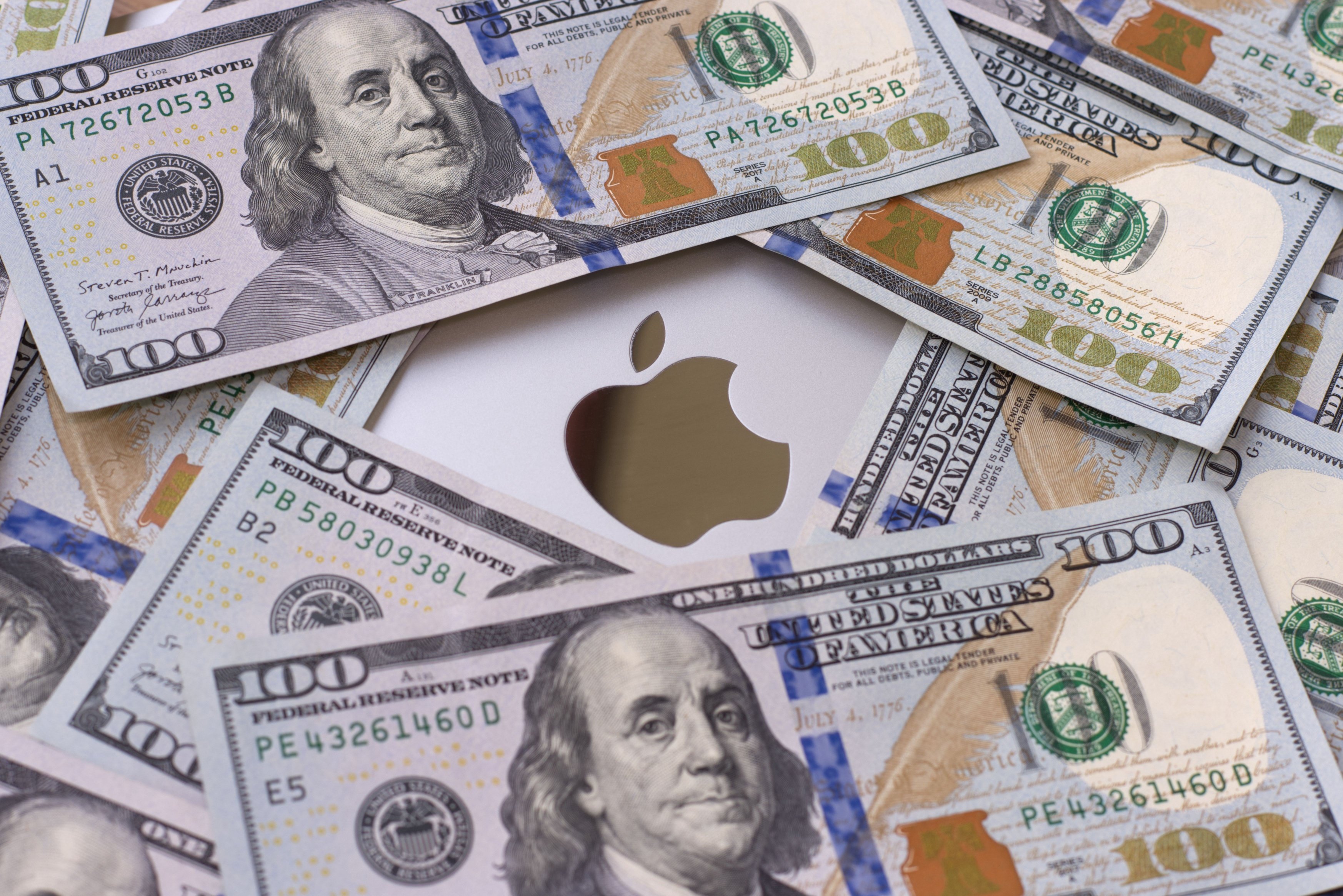 Des billets de 100 dollars éparpillés autour du logo Apple © Shutterstock