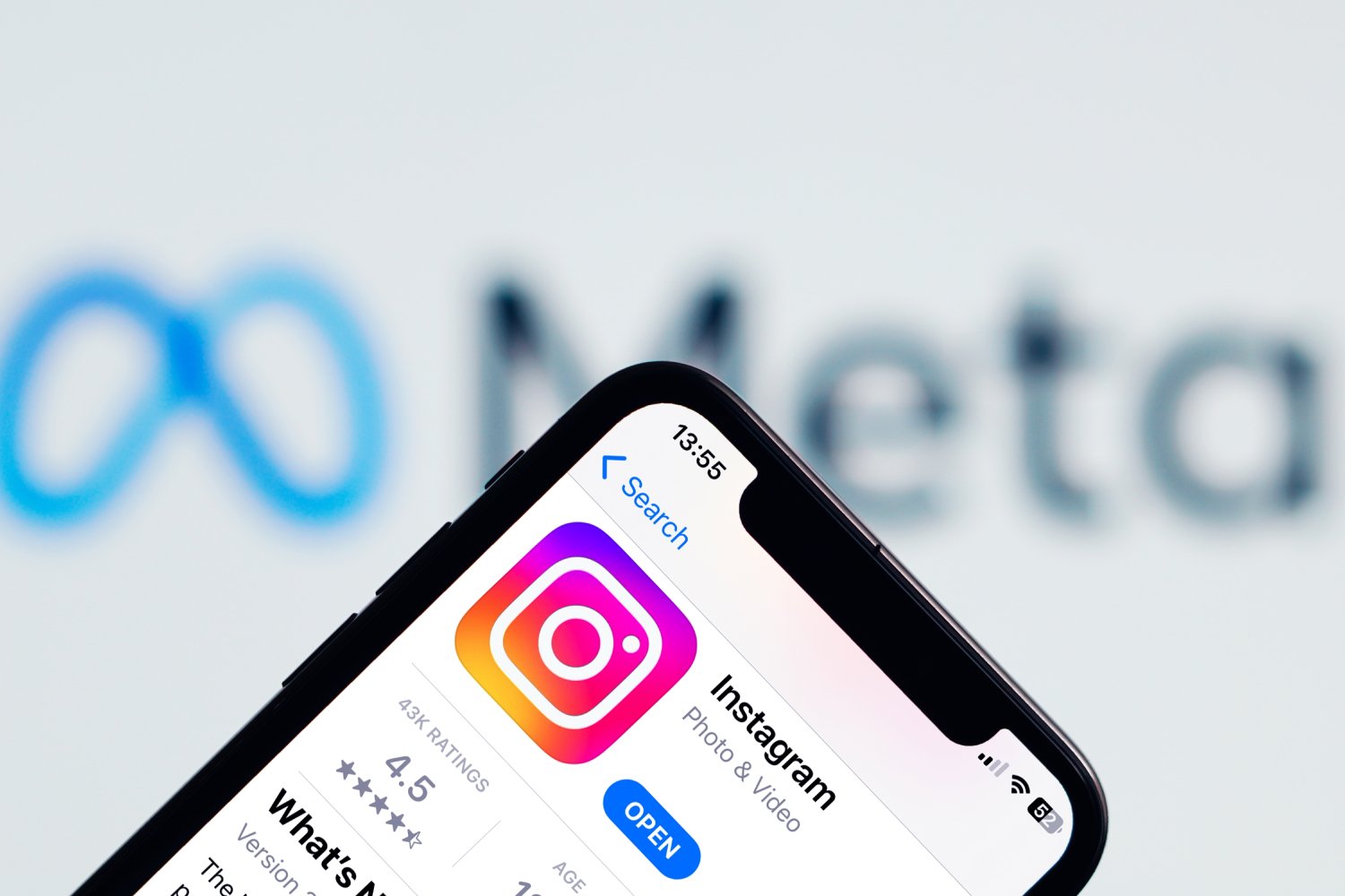 L'application Instagram s'affiche sur un iPhone, avec le logo de Meta en fond © PatrickAssale / Shutterstock