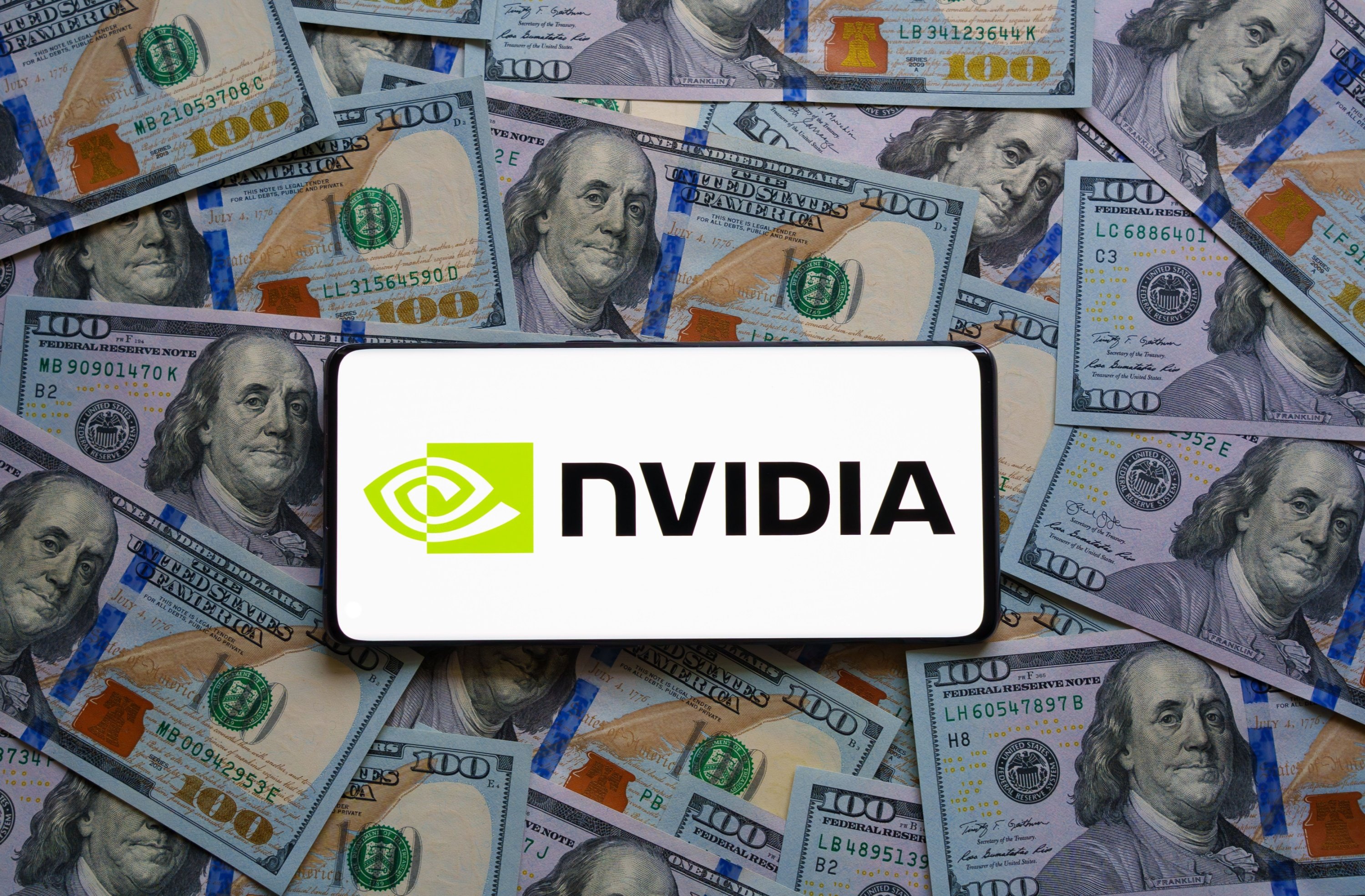 Un smartphone où s'affiche le logo de NVIDIA est posée sur des liasses de billets © Ascannio / Shutterstock.com