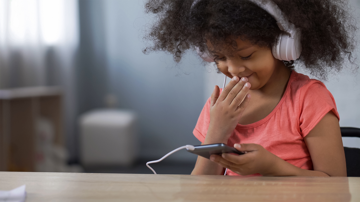 Little black girl smiling while surfing internet on smartphone, parental control-1.png