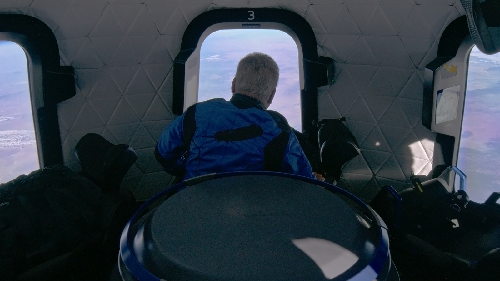 William Shatner observant la Terre  travers un hublot de New Shepard © Blue Origin