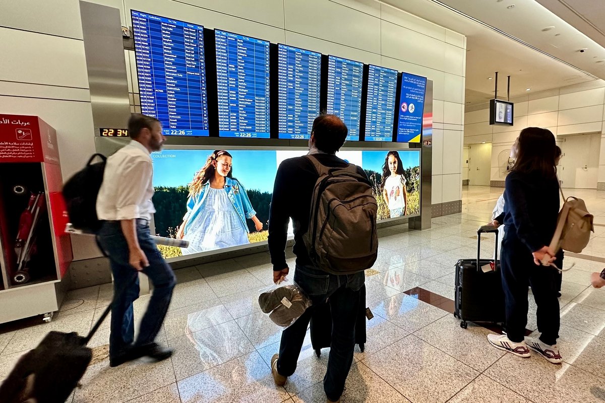 Des personnes regardent leur vol sur l'écran d'un aéroport © M. Sam / Shutterstock.com