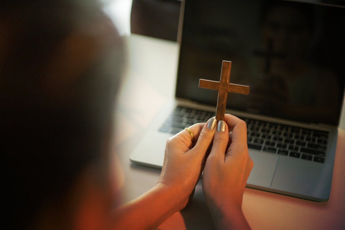 Une femme priant devant son ordinateur portable © ftimelexandru88 / Shutterstock