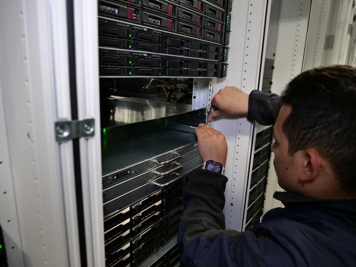 Un technicien est en train d'isoler les bords du rack avec des feuilles d'aluminium, pour empêcher forcer l'air froid à traverser les serveurs pour les maintenir à une température de fonctionnement optimal © Alexandre Boero / Clubic