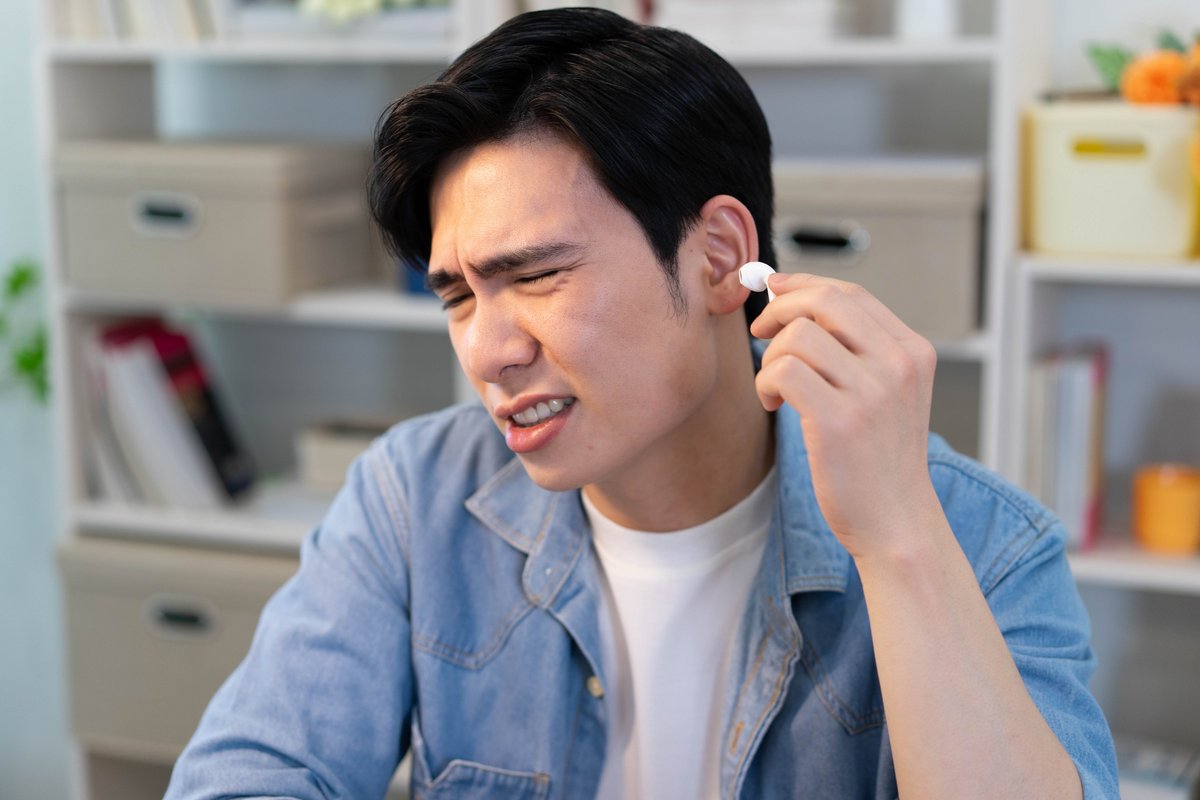 Un homme gêné par son écouteur sans fil. © Shutterstock