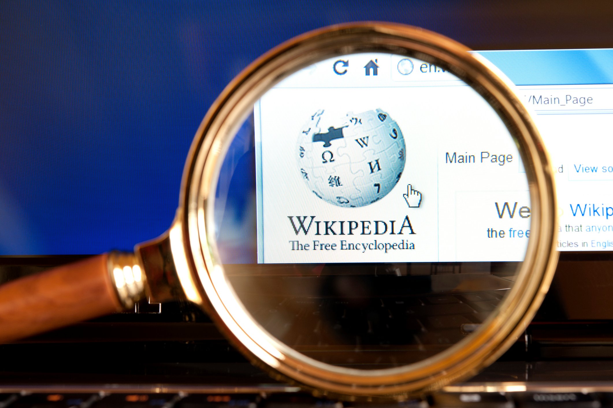 Une loupe est dressée devant une page Wikipedia © brightstars / iStock