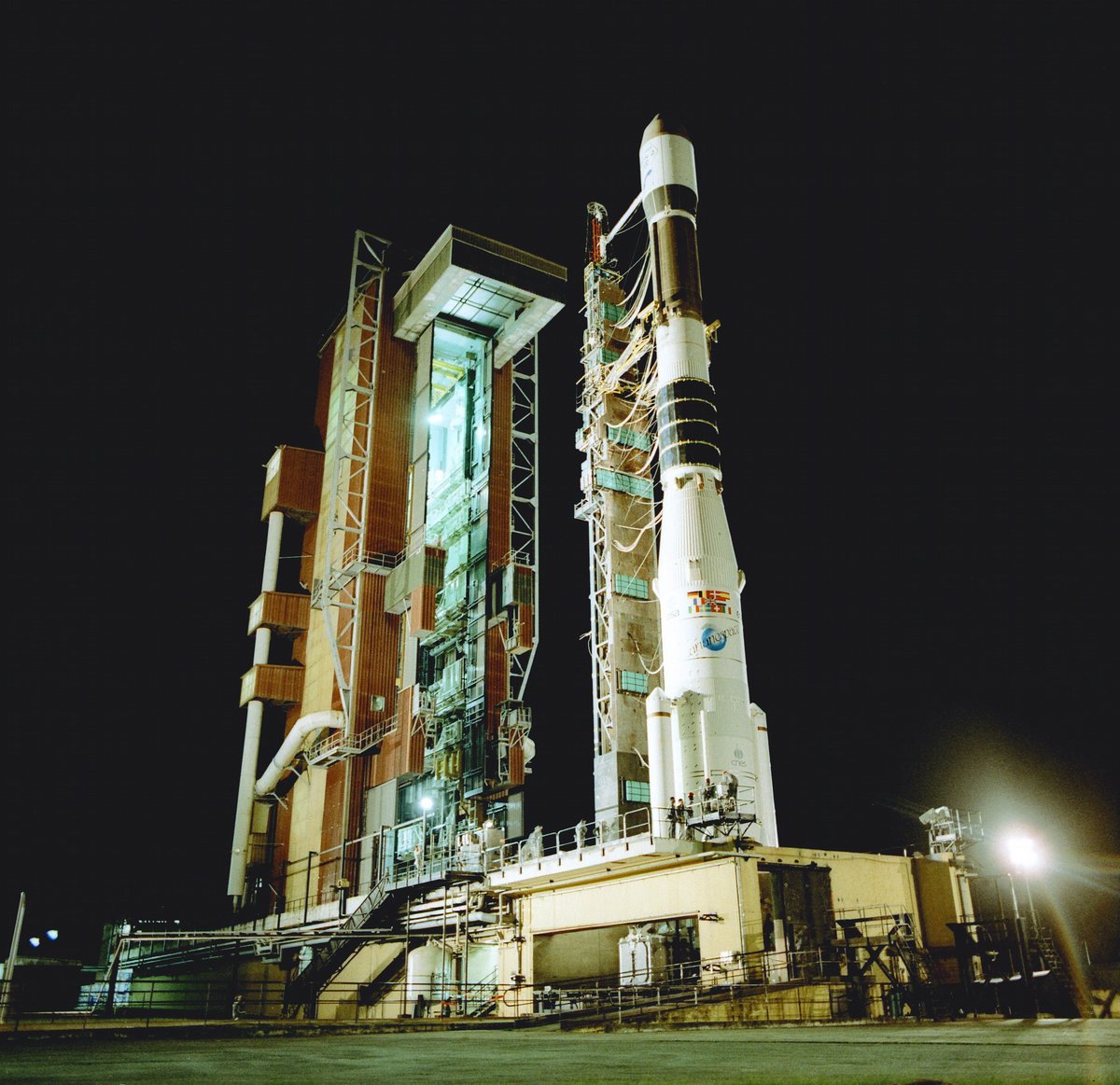 Fusée Ariane 3 sur son pas de tir. On distingue nettement les deux petits boosters de part et d'autre du premier étage. Chacun d'entre eux pèse environ 7 tonnes. Le volume du premier et du deuxième étage reste similaire à ceux d'Ariane 1. Crédits: Ariane Group