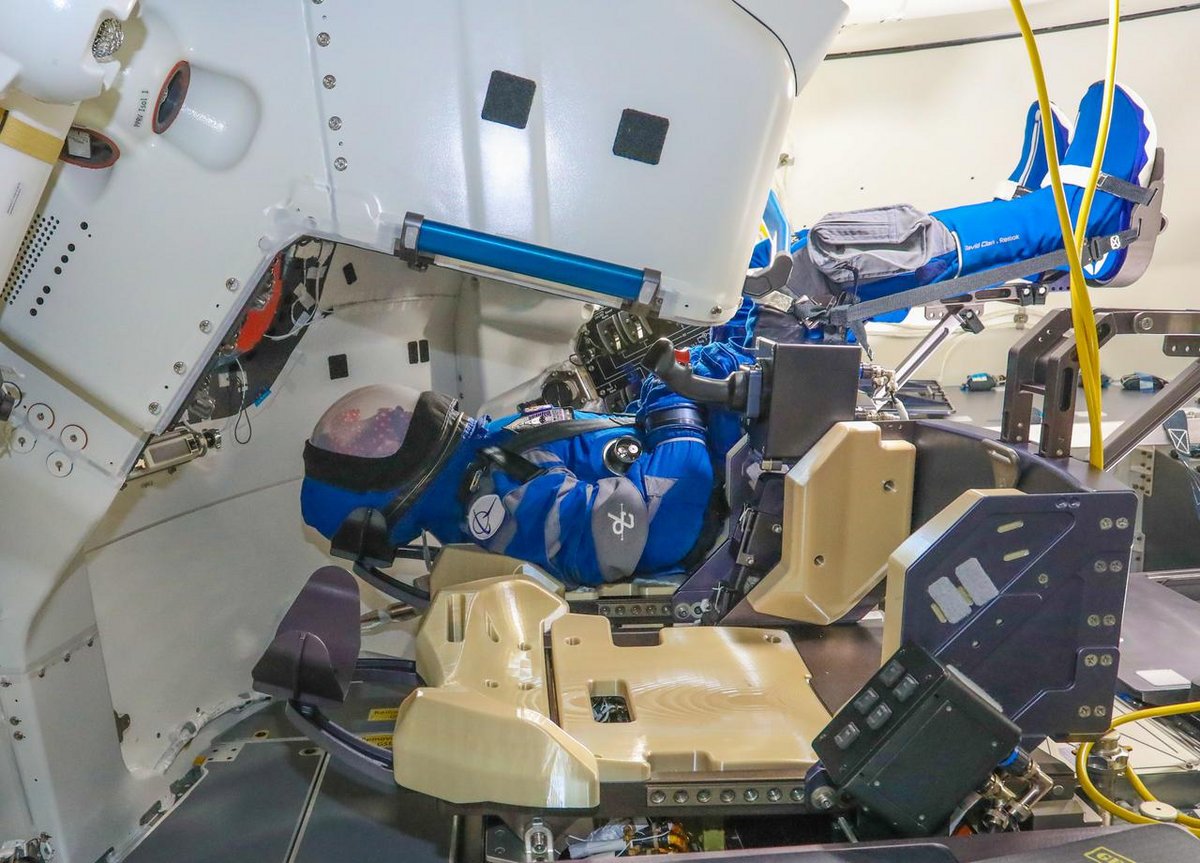 Le mannequin &quot;rosie&quot; à l&#039;intérieur de la capsule Starliner pour son vol de test.  Il est équipé de la combinaison de boeing, et se tient devant les commandes de la capsule. Crédits Boeing