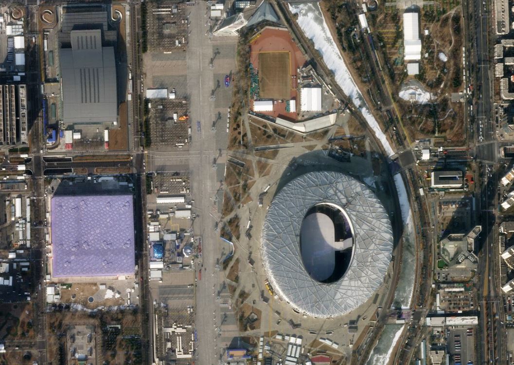 À gauche du stade « nid d&#039;oiseau », on retrouve en violet le National Aquatics Center transformé en version hiver et devenu Ice Cube, qui accueillera le curling, et le National Indoor Stadium (en haut à gauche) qui hébergera une partie du championnat de hockey. Crédit : Roscosmos