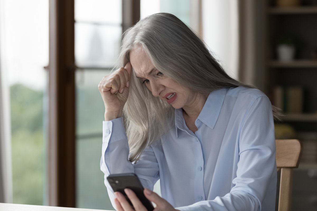 Une femme regarde soucieuse son smartphone © Shutterstock