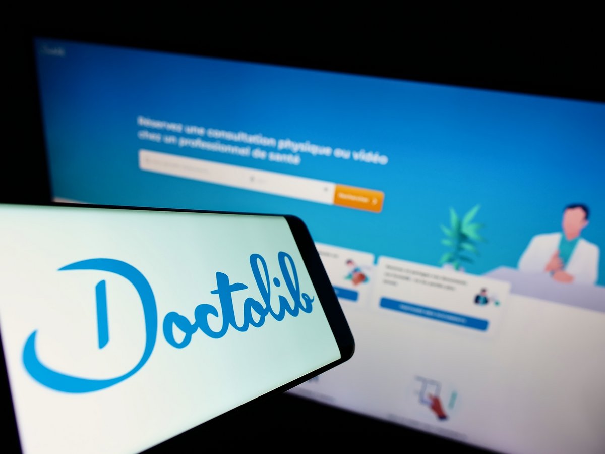 Le logo de Doctolib sur un smartphone, face à son interface bureau © T. Schneider / Shutterstock.com