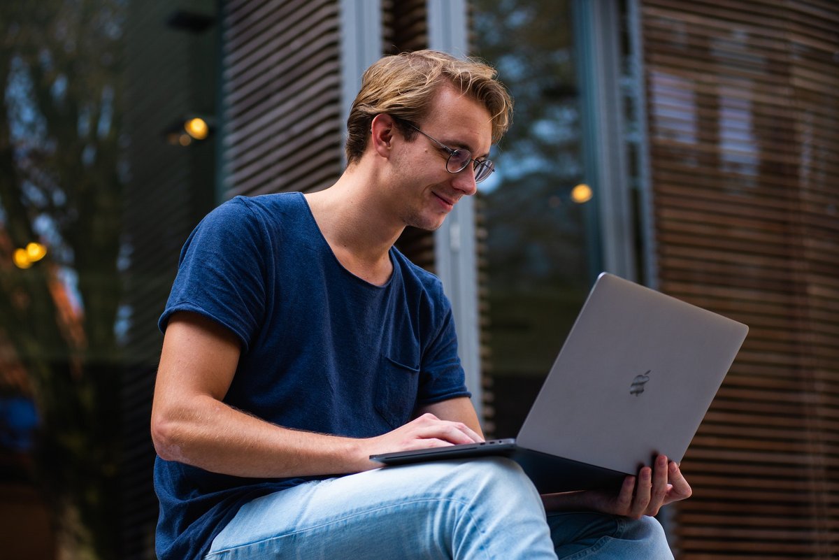 Homme souriant devant un Mac © Buro Millenial / Pexels 