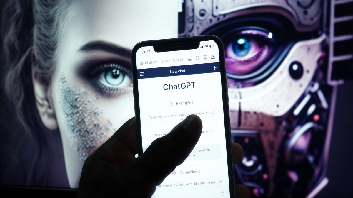 L'application ChatGPT affichée sur un smartphone, avec derrière une personne qui regarde fixement © Patrickx007 / Shutterstock