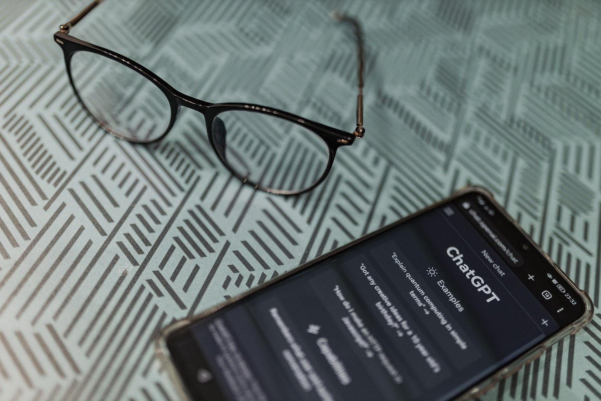 Un smartphone où ChatGPT est activé voisine une paire de lunettes © Matheus Bertelli / Pexels