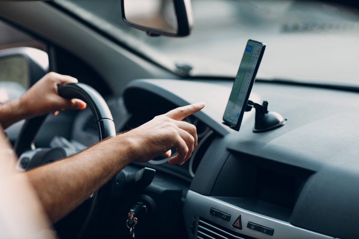 Une personne utilisant son smartphone au volant © Shutterstock