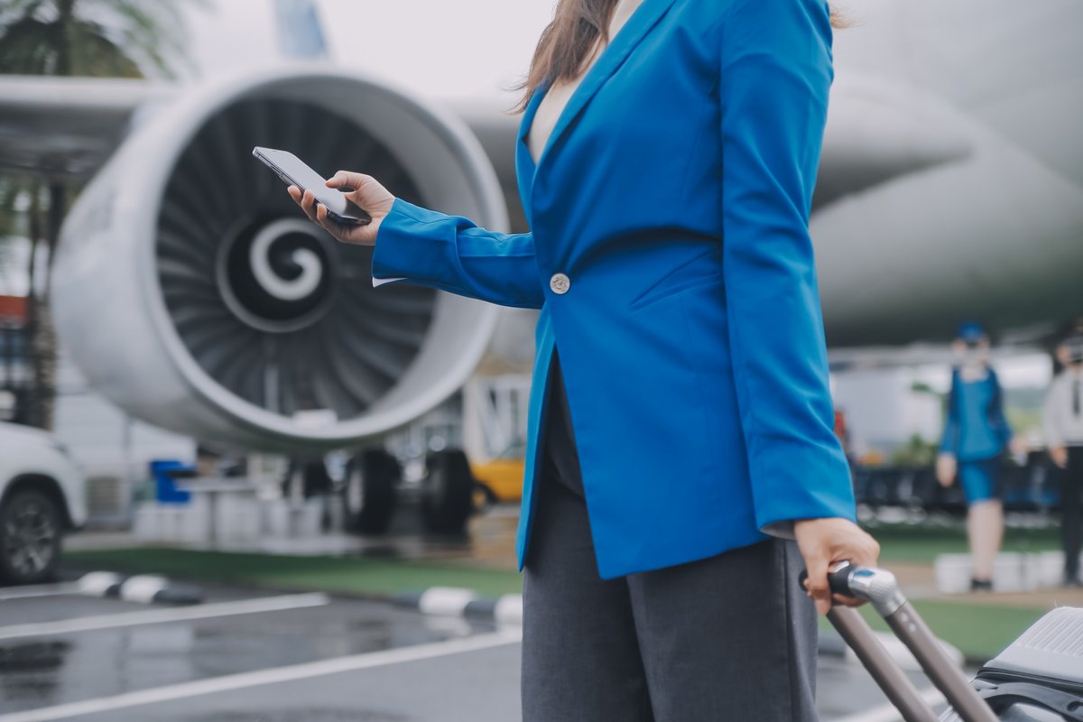 Une femme, smartphone en main sur le tarmac d'un aéroport © ARMMY PICCA / Shutterstock