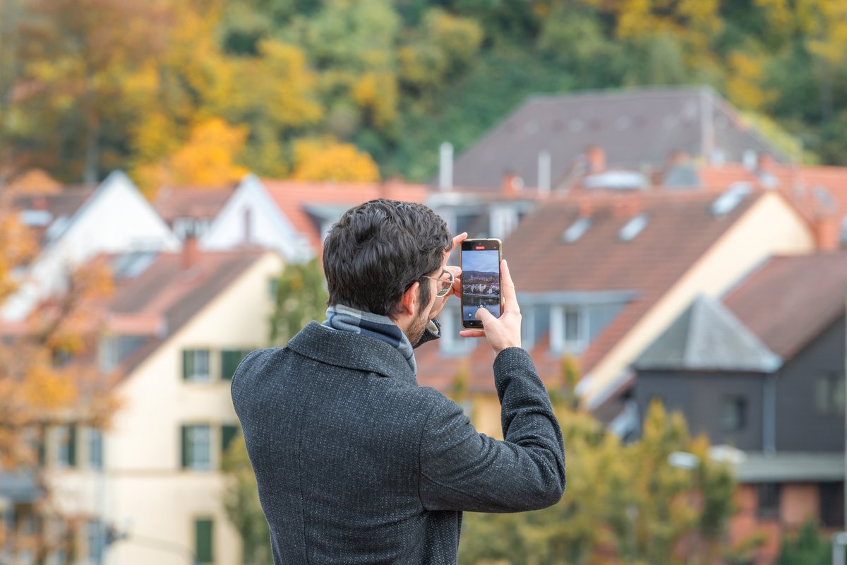 Un homme prenant en photo des maisons © DirkVG / Shutterstock