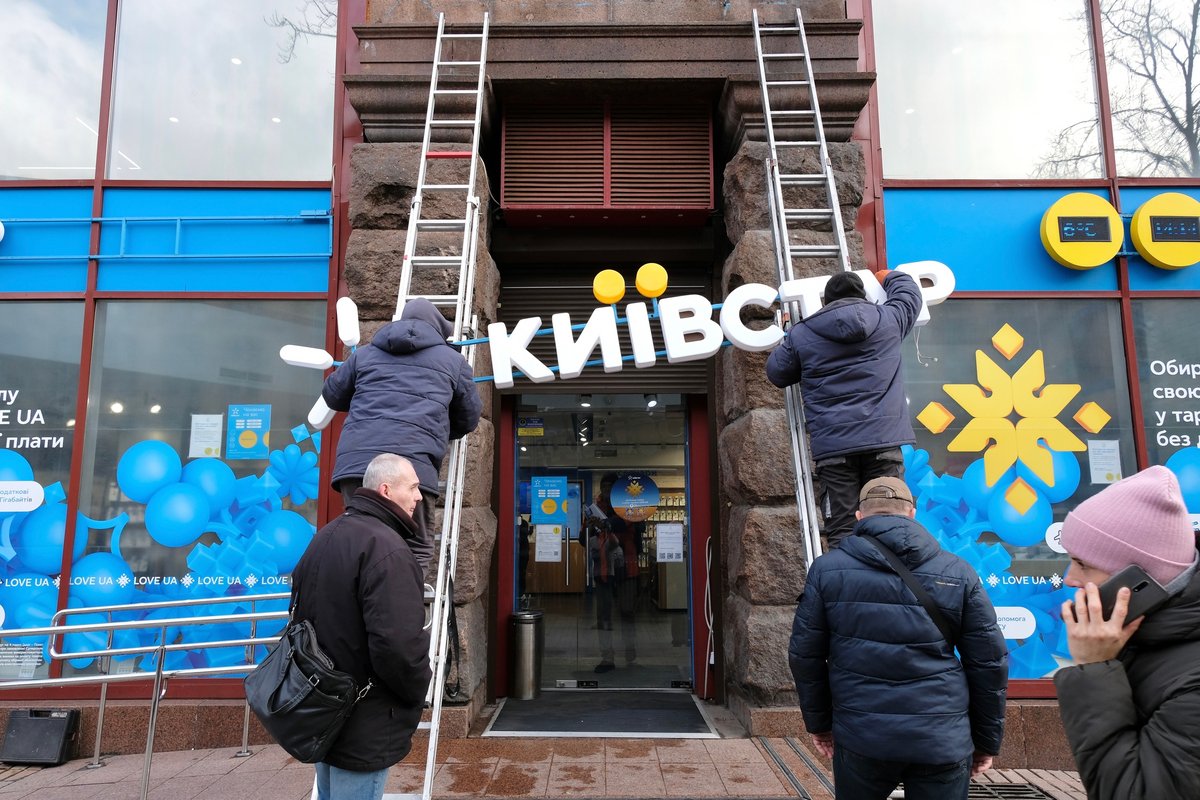 À Kiev, deux ouvriers dans la rue grimpant sur les échelles avec le panneau de la boutique Kyivstar à attacher sur la façade d'un bâtiment © Doroznik / Shutterstock