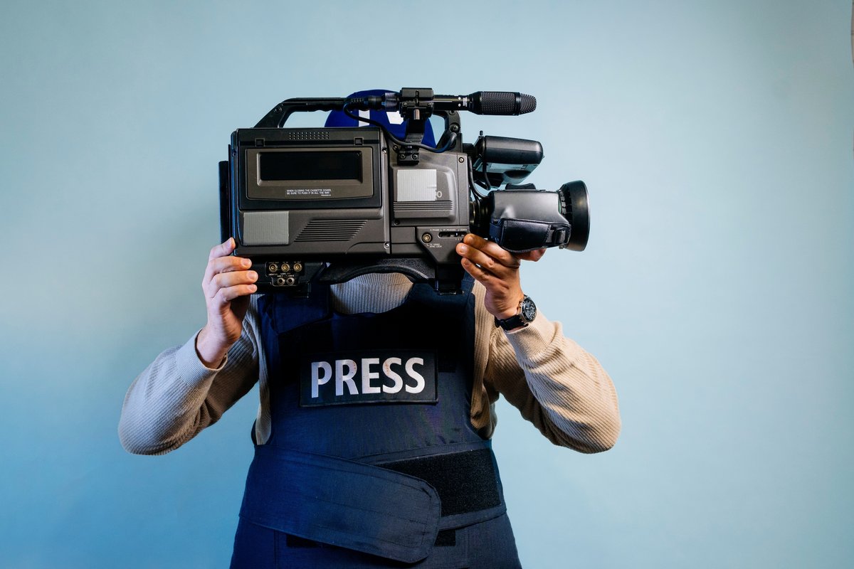 Journaliste dans un gilet pare-balles tenant une caméra © Jose Luis Carrascosa / Shutterstock