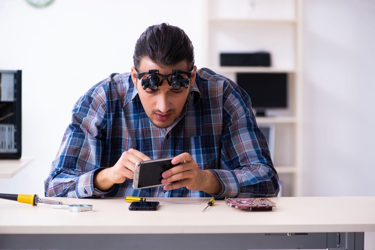 Un jeune technicien réparant un téléphone portable © Elnur / Shutterstock