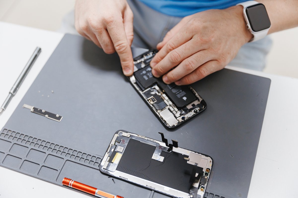 Un technicien en train de réparer un iPhone endommagé © Parilov / Shutterstock